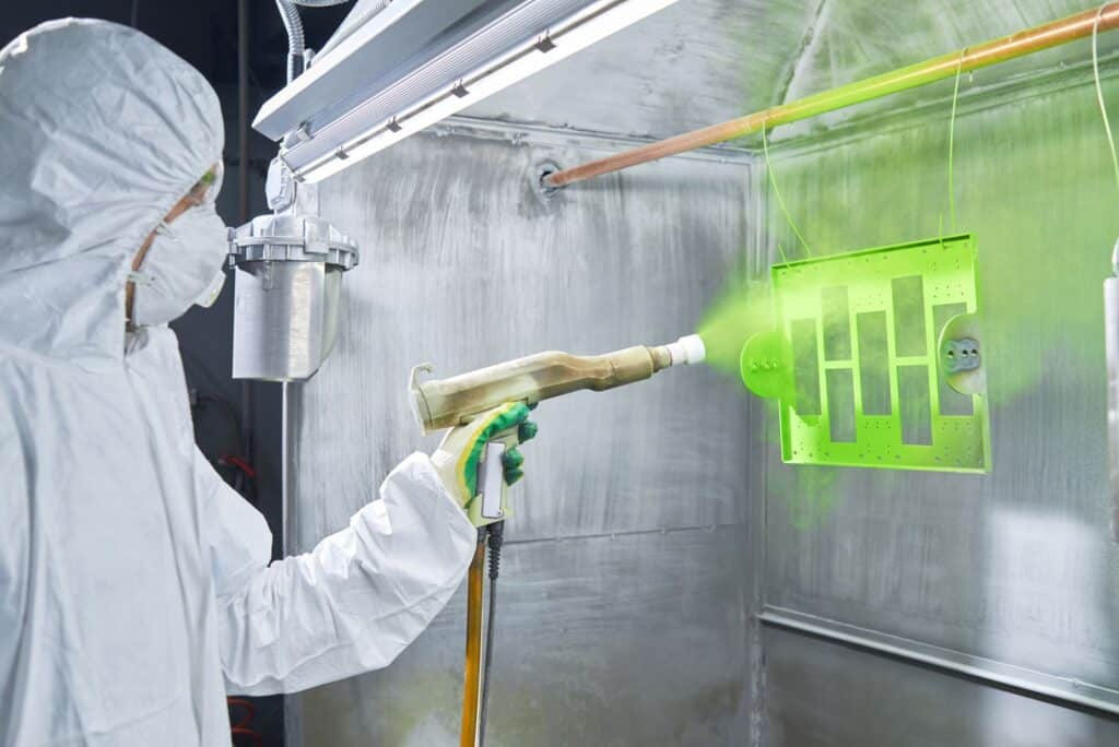 specialist powder coating a part in full ppe