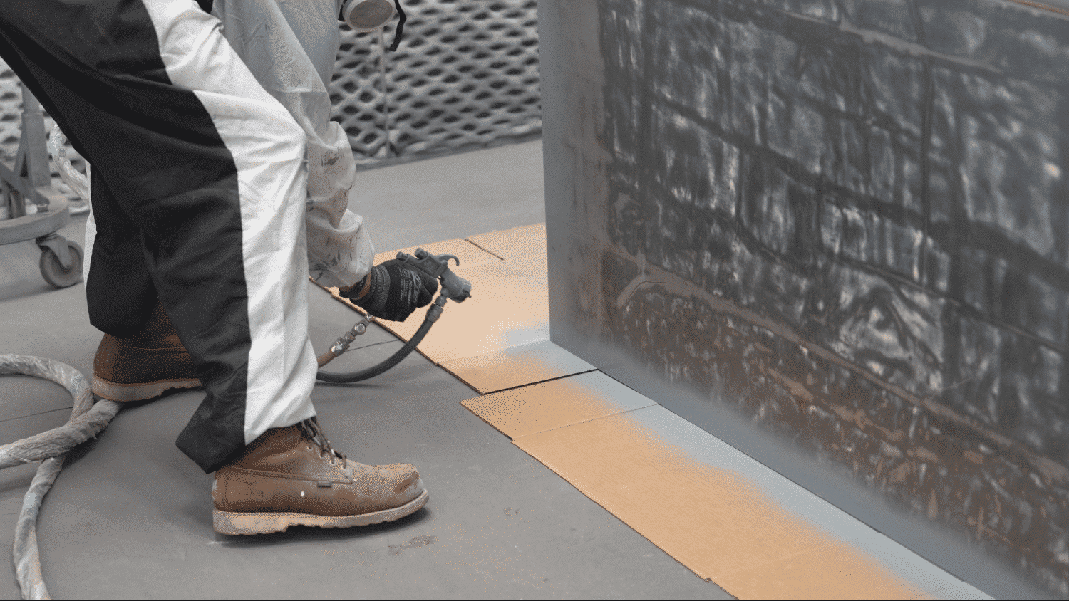 specialist painting the bottom of a structure in ppe