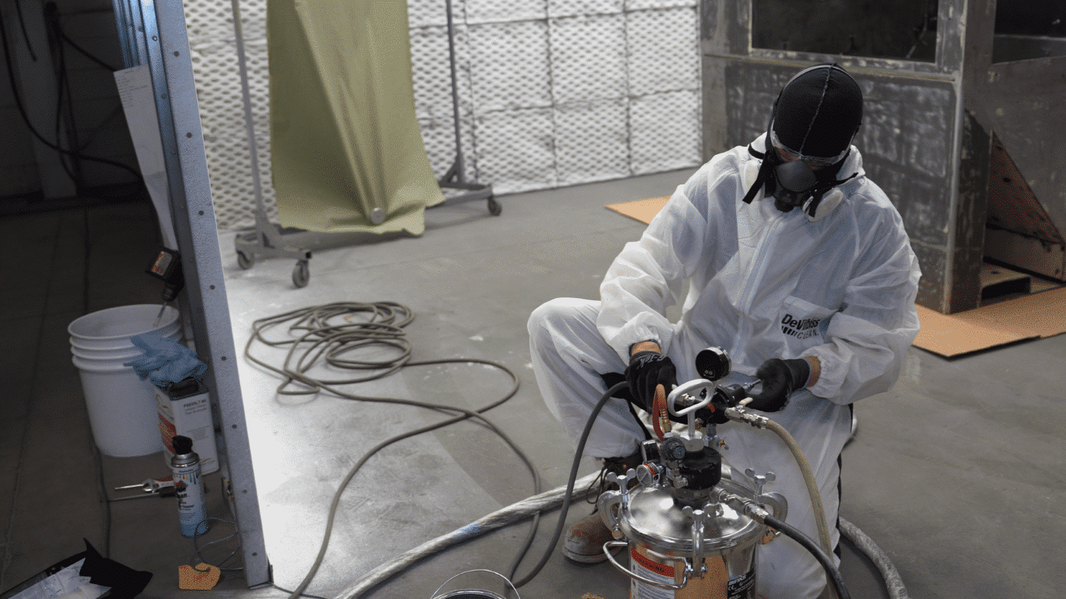 specialist calibrating pressure valve in a paint pot in full ppe